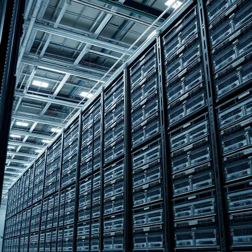 View of multiple rows of server racks and blade enclosures in a large data center.