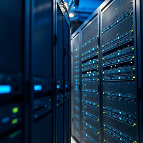 Rows of server racks in a data center, illuminated by blue and white lights.